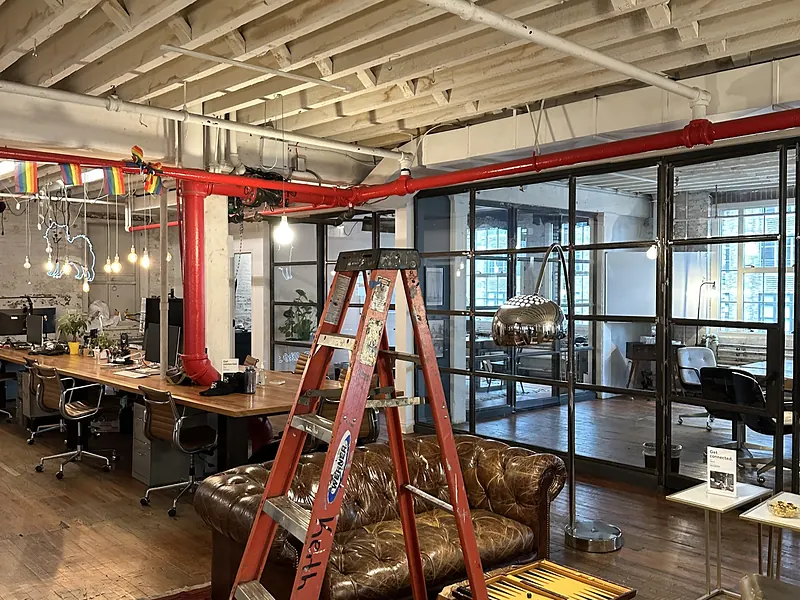 Open loft office with exposed wood beams, desks and a ladder