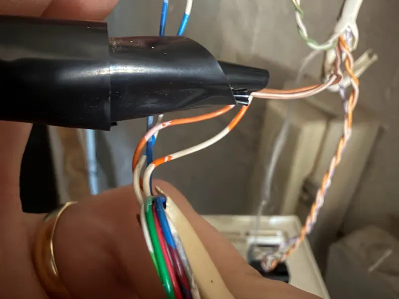 Hands re-terminating the wire pairs of a network cable