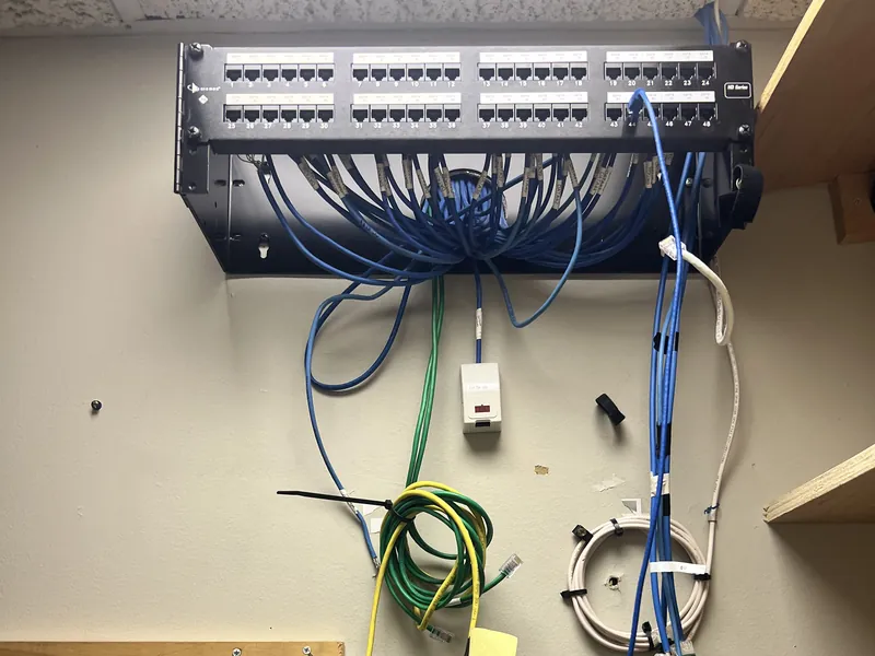 Old patch panel on the wall with loose blue cables hanging below it