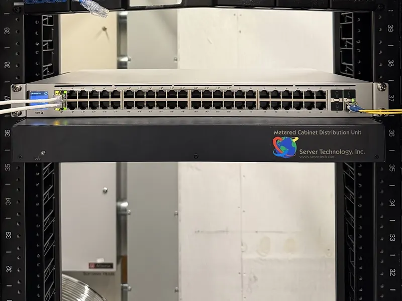 UniFi 48-port PoE switch with a fiber uplink in a floor-standing rack