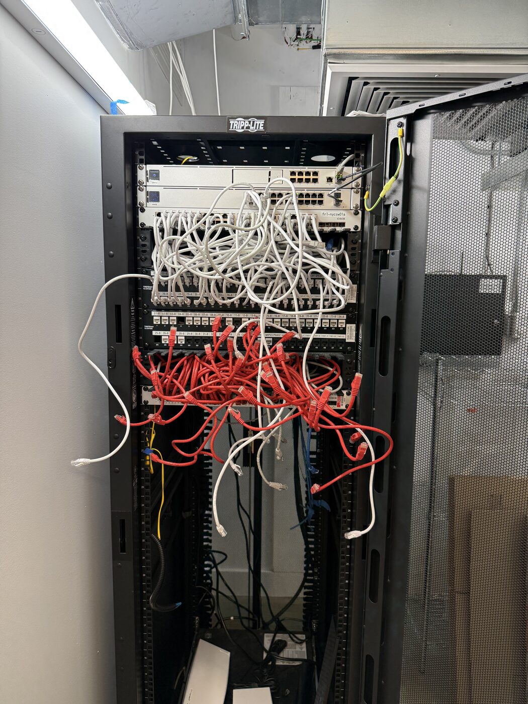 Network rack before cleanup, tangled patch cables in front of UniFi gear