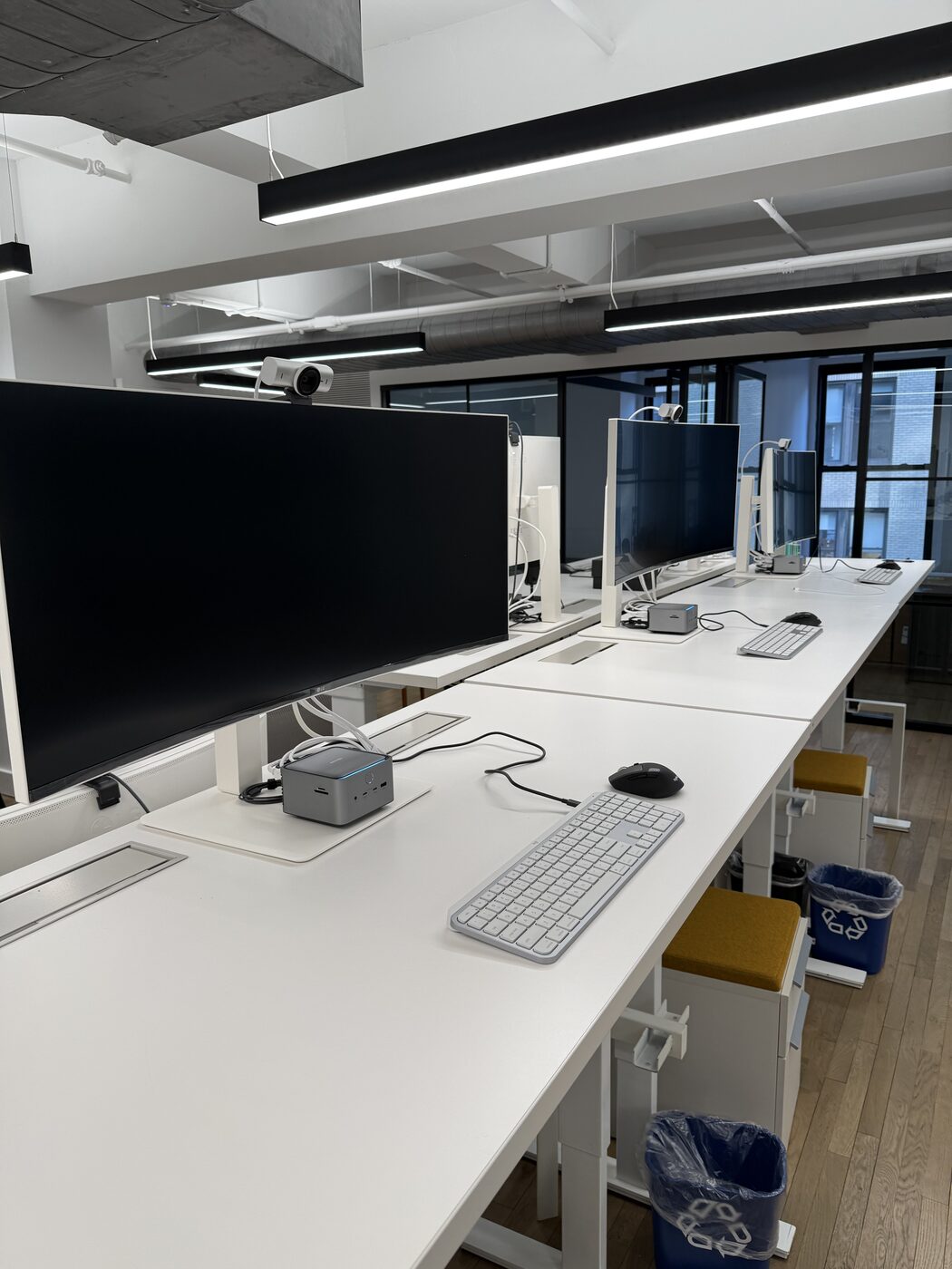 Row of standing desks with monitors and cable management in an open office